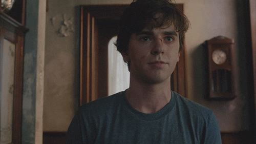 TV gif. Freddie Highmore as Norman in Bates Motel smiles sheepishly as he shrugs his shoulders.