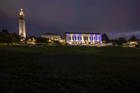 Text gif. Photo of University of California Berkeley campus at night. Text "Welcome back!" appears handwritten in school colors blue and yellow then disappears. Two hand drawn hearts appear flashing in blue and yellow.