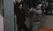 Seinfeld gif. Jerry Seinfeld as Jerry and Jason Alexander as George bend their knees and pump their fists in excitement.