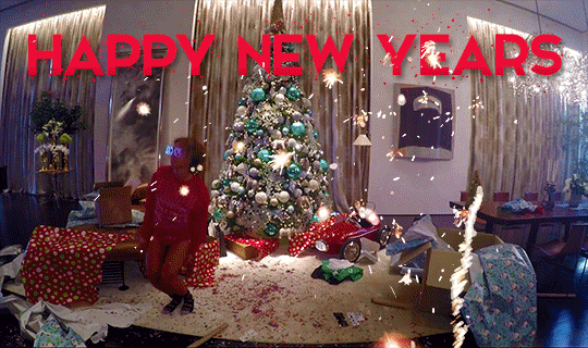 Celebrity gif. Clip from Beyonce's video for "7/11" where she is hopping out of Christmas boxes around a living room while wearing pajamas. Fireworks are overlaid, and text says "Happy New Years."