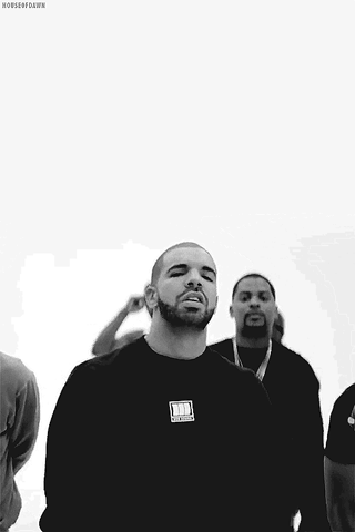 Music video gif. A black-and-white scene of Drake and several others against a white background. We zoom in slightly on Drake, who looks at us as he puts his hands together in prayer.