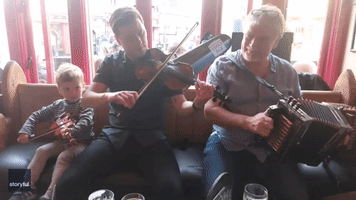 Toddler Hones His Fiddle Skills During Live Music Session at Irish Pub