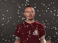 Video gif. A man looks around gleefully before smiling at us as digital snow falls around him. 