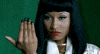 Celebrity gif. Nicki Minaj glares menacingly ahead. She closes the fingers of her outstretched hand as if signaling, bring it on.