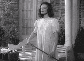 Movie gif. Katharine Hepburn as Tracy Lord from The Philadelphia Story smiles sweetly before splitting a golf club in half with her knee. Her expression immediately drops into one of anger as she throws the broken club to the ground.