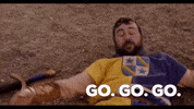 Movie gif. Joe Lo Truglio, as Kuzzik in Role Models, lying on the ground, lifting his head impatiently and saying "go, go, go."