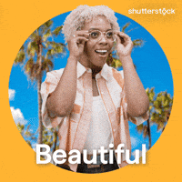 Sponsored gif. Woman takes off her glasses and looks around with a wide-eye expression of wonder on her face. The background behind her features palm trees on a sunny day. Text reads, “Beautiful.”