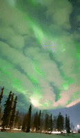 Aurora Borealis Dazzle Behind Scattered Clouds in North Pole, Alaska