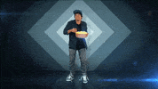 Video gif. Man dances, bopping side to side, with a bowl of popcorn in his hand. He take a handful of popcorn and eats it while dancing.