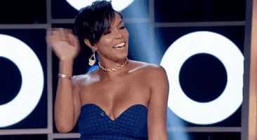 Reality TV gif. Letoya Luckett on Hip Hop Squares looks out at the crowd with a beautiful smile and waves. 