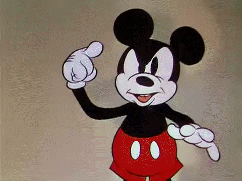 Disney gif. Mickey Mouse grins at us as he spins a finger pointing to his head, as if to say, "Crazy."