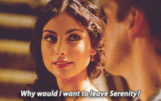 TV gif. Morena Baccarin as Inara Serra on Firefly looks over at Nathan Fillion as Malcolm Reynolds with love and devotion in her eyes. She smirks and shakes her head lightly as she says, “Why would I want to leave Serenity?”