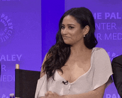 Celebrity gif. Shay Mitchell juts her head out, frowns and lifts her eyebrows, and shrugs with her palms up.