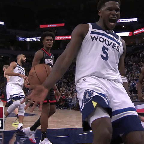 Sports gif. Anthony Edwards of the Minnesota Timberwolves is on the court and he's just made a slam dunk. He stretches out his arms and whoops in celebration as he walks towards the camera.