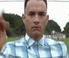 Movie gif. Tom Hanks as Forrest Gump runs across a football field in his normal clothes while staring straight ahead.