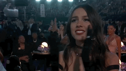 Celebrity gif. Olivia Rodrigo is at the Grammy's and she looks compassionate as she gives a standing ovation while whooping.