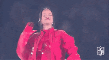 Video gif. Rihanna at the Super Bowl halftime show puts one hand behind her head and one hand on her hip, slowly walking forward with cool confidence, doing a face like she smells something bad, then curling up her top lip like she's feeling herself. 