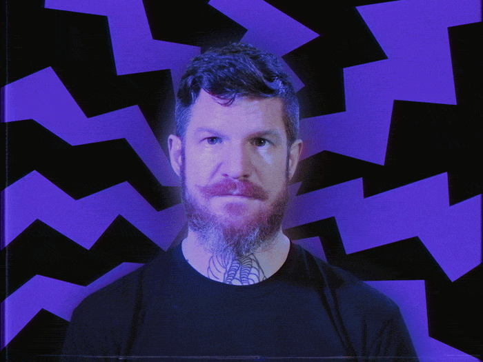 Celebrity gif. Andy Hurley from Fall Out Boy gives a shocked expression as he stands in front of a background that shows lightning bolts that resembles electric shocks. 