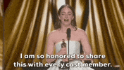 Oscars 2024 GIF. Emma Stone wins Best Actress. She clutches the trophy with both of her hands and uses it to punctuate her statement, which reads, "I am so honored to share this with every cast member."