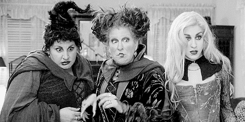 Movie gif. Sarah Jessica Parker as Sarah Sanderson, Bette Midler as Winifred Sanderson, and Kathy Najimy as Mary Sanderson in Hocus Pocus glare at something with wide eyes and they all take a cautious step backwards.
