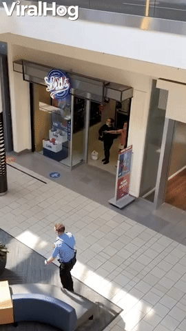 Man Casually Strolls Past Woman Pointing Gun Inside Mall