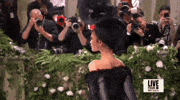 Met Gala 2024 gif. Zendaya, turns toward us, revealing her big floral hat.