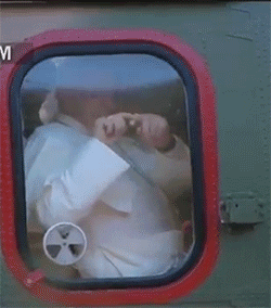 Political gif. Pope Francis draws a heart with his fingers from his helicopter window.