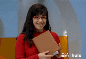 TV gif. America Ferrera as Betty in Ugly Betty. She grins happily while giving us a thumbs up, which she puts close to her face.