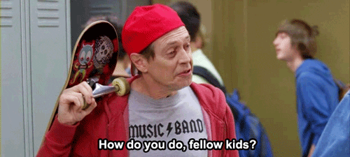TV gif. Slinging a skateboard over his shoulder, Steve Buscemi, as Lenny in 30 Rock, attempts to pose as a teenager, wearing a red backward baseball cap and a t-shirt that says “Music Band” as he says, “How do you do, fellow kids?”