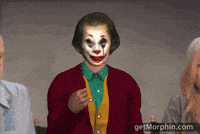 Digital art gif. A 3D rendering of Joaquin Phoenix's Joker tossing gold confetti into the air, superimposed between two live action people.