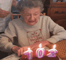 Video gif. An old woman goes to blow out the candles on her 102nd birthday cake. As she purses her lips to blow, her dentures fall out and onto the table. She scrambles to catch them and then she laughs out loud.