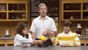 SNL Gif. Jason Sudeikis is dressed like a science teacher and smacks Cecily Strong’s and Mikey Day’s hands away from a model of the solar system.