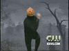 Video gif. Pumpkin Dance man in a black unitard with a jack-o-lantern on his head does dances from side-to-side in front of a graveyard backdrop. 