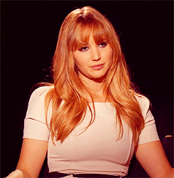 Celebrity gif. Actress Jennifer Lawrence wryly smiles during an interview with an annoyed expression on her face.