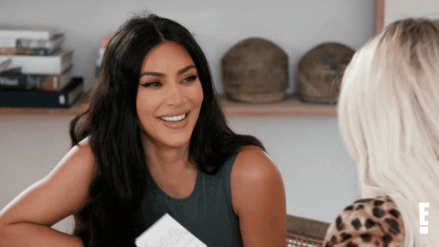 Reality TV gif. Kim Kardashian on Keeping Up with the Kardashians, rests her hand on her chest as she leans forward and laughs.