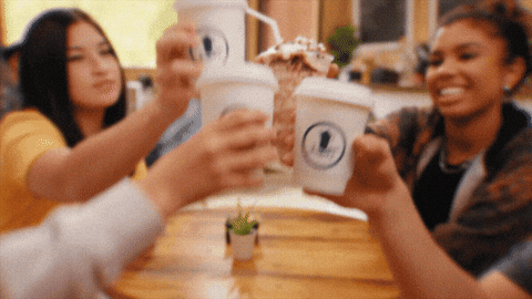 A group of friends are sharing a coffee toast at a cafe.