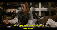 Movie gif. James Franco as Saul Silver in Pineapple Express sits on a couch, eating something while he cattily says, "I thought hurricane season was over."