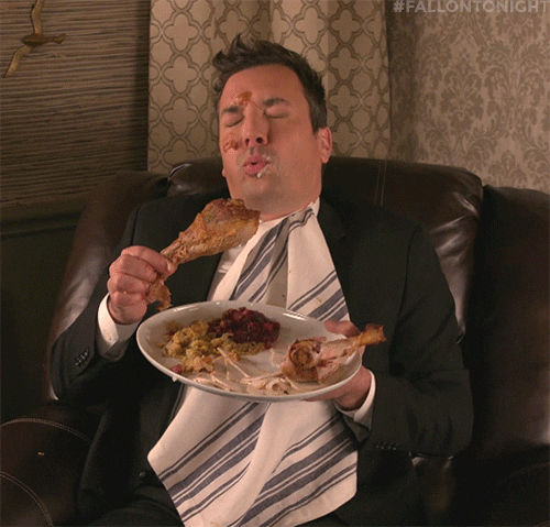TV gif. Jimmy Fallon as host of the Tonight Show sits in a large leather recliner with a messy plate of food in his hand, some of the food smeared on his cheek and forehead. He looks at the turkey leg he's holding before groaning--his eyes are bigger than his stomach!
