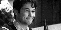 Movie gif. Joseph Gordon-Levitt as Tom in 500 Days of Summer smiles while raising and tilting his beer bottle to cheers.