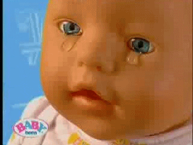 Video gif. A close up shot of a plastic baby doll with very human-like eyes. Fat tears spill from the eyes and its mouth is slightly agape. 