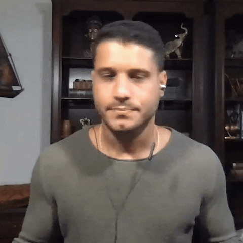 Reality TV gif. Cody Calafiore from Big Brother wears wired ear bubs, sarcastically bobbing his head from side to side as he says, “Cool."