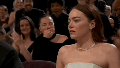 Oscars 2024 GIF. The crowd erupts into a standing ovation around Emma Stone, who wins Best Actress. She stares around her in disbelief and slowly gets up to embrace and kiss her partner. 