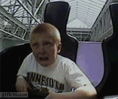 Video gif. Boy sits in the cart of a roller coaster that spins the cart around as it goes around the track. The boy screams and cries as he holds on for dear life.