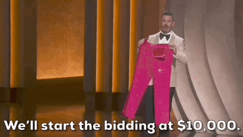 Oscars 2024 gif. Jimmy Kimmel wears a white blazer as he holds up a pair of Ryan Gosling's hot pink Ken pants for the crowd to take a gander. He says, "We'll start the bidding at $10,000."