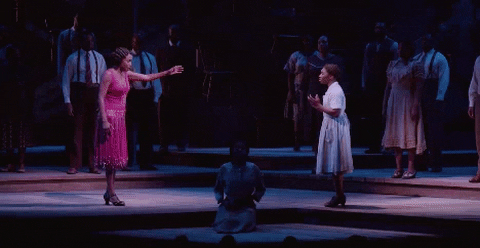 Broadway gif. Heather Headley as Shug Avery in The Color Purple walks from the left with one arm outstretched toward Cynthia Erivo as Celie walking from the right. They meet in the middle and embrace emphatically.