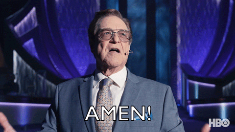 TV gif. Actor John Goodman as Dr. Eli in The Righteous Gemstones wears tinted Aviator glasses and a nice suit, with an over ear microphone next to his mouth. He raises his arms up to the heavens, looks up, and shouts, “Amen!”
