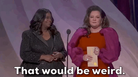 Oscars 2024 GIF. Melissa McCarthy nervously clutches the Oscar winner envelope in her hand as she blinks with sudden awareness, looking around and saying, "That would be weird." Spencer stands next to her and smiles and nods in agreement.