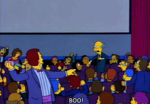 The Simpsons gif. Mr Burns standing up in a theater, protecting his head as other attendees throw food and drinks at him. Text, "Boo!"