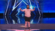 TV gif. Leroy Patterson stands on stage with his shirt off lowering his arms dramatically, looking sad. He turns as if to leave with his eyes shifting sideways.