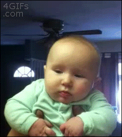 Video gif. Man holding a baby under the arms gives the baby a big cheek kiss, and then the baby sticks out his lower lip, appearing sad.
